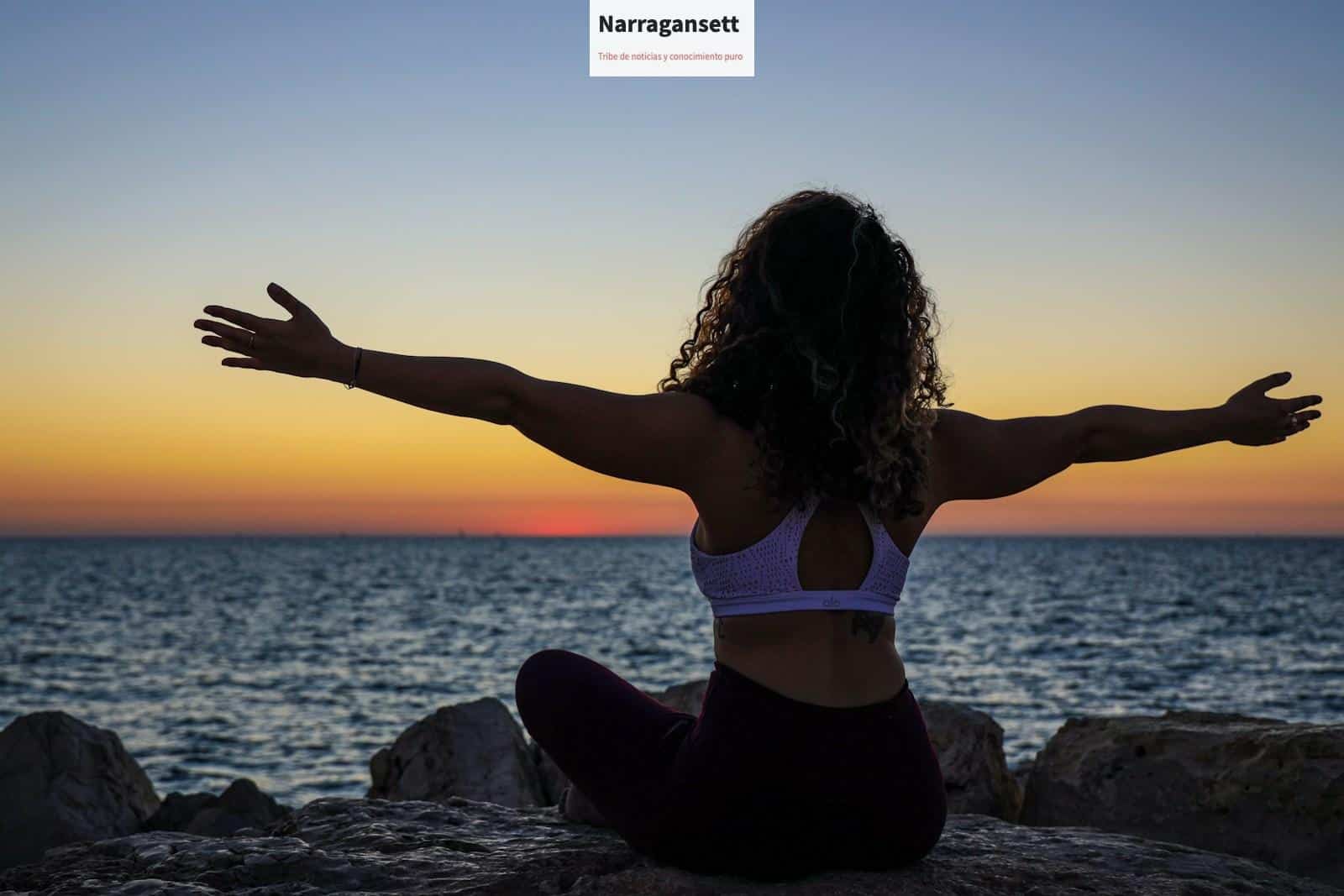 woman wearing sports bra sitting in front of the ocean