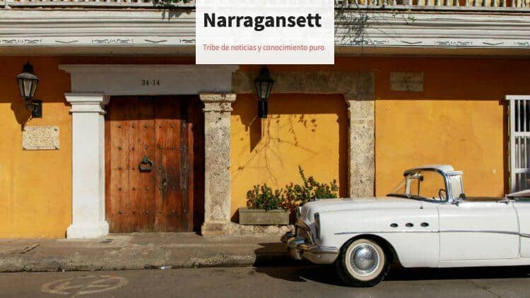 Classic white convertible parked in front of a historic, colorful building facade under daylight.