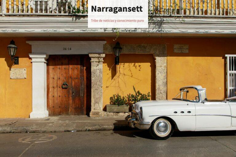 Classic white convertible parked in front of a historic, colorful building facade under daylight.