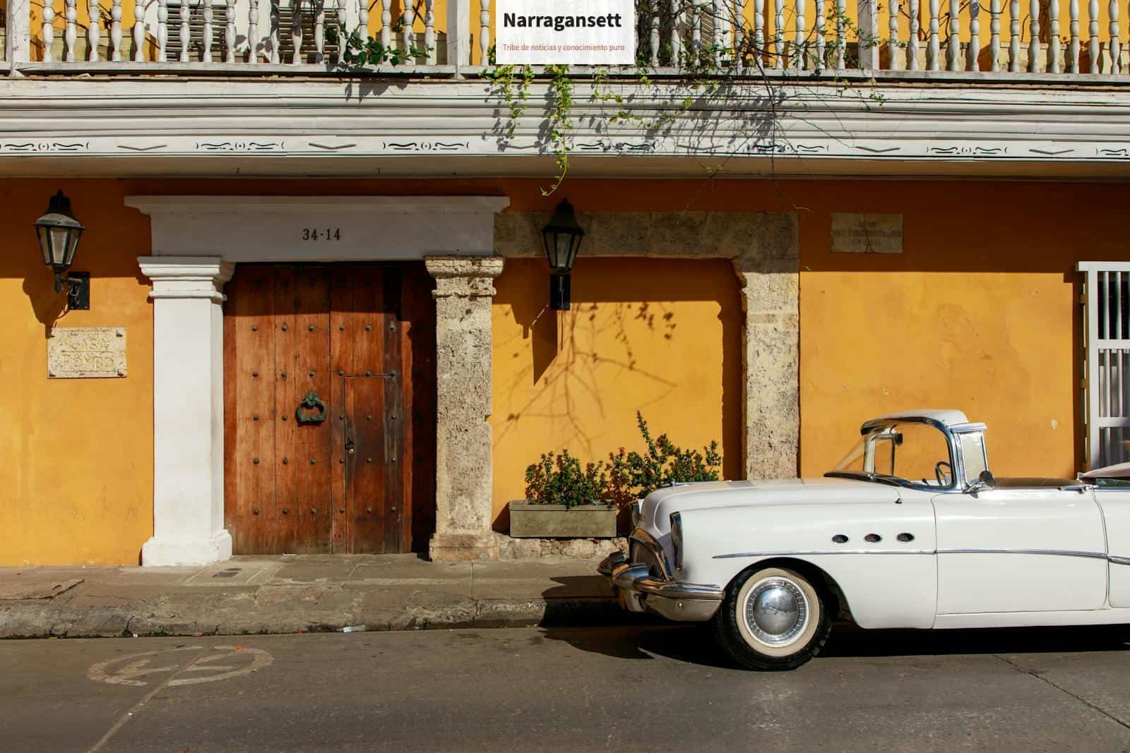 Classic white convertible parked in front of a historic, colorful building facade under daylight.